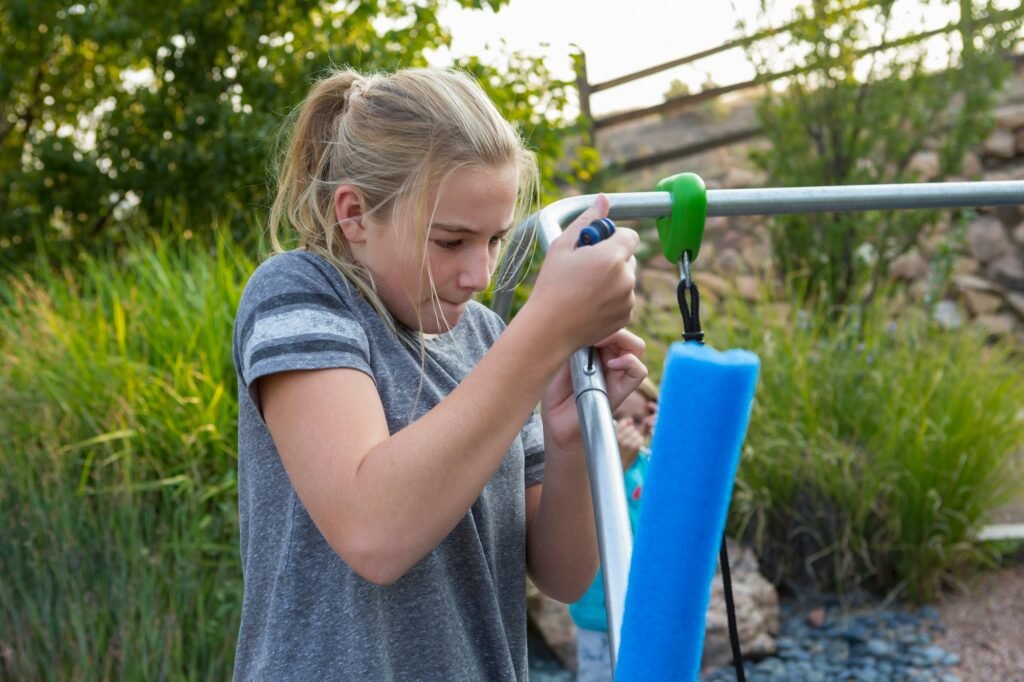 11 year old girl fixing child's swing in backyard